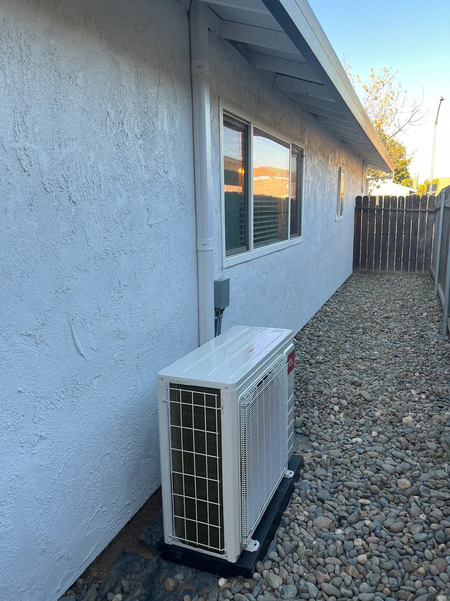 27k BTU multi-zone mini-split outdoor condenser mounted on a pad beside the house