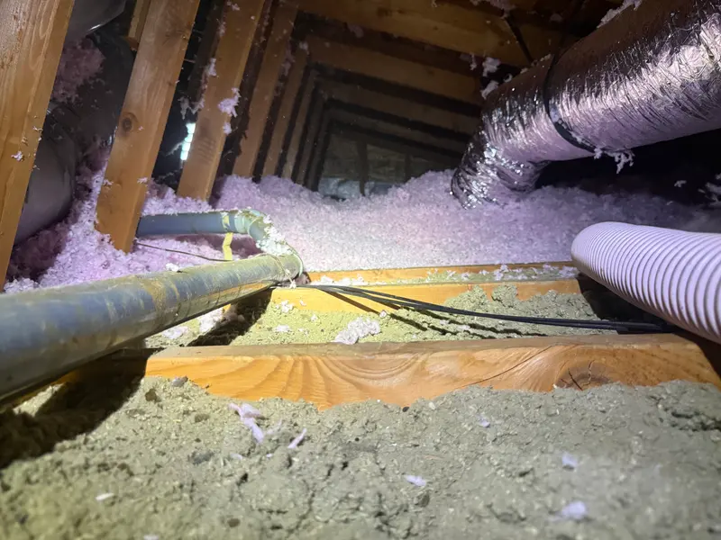 Attic duct trunk and refrigerant line set above blown-in insulation