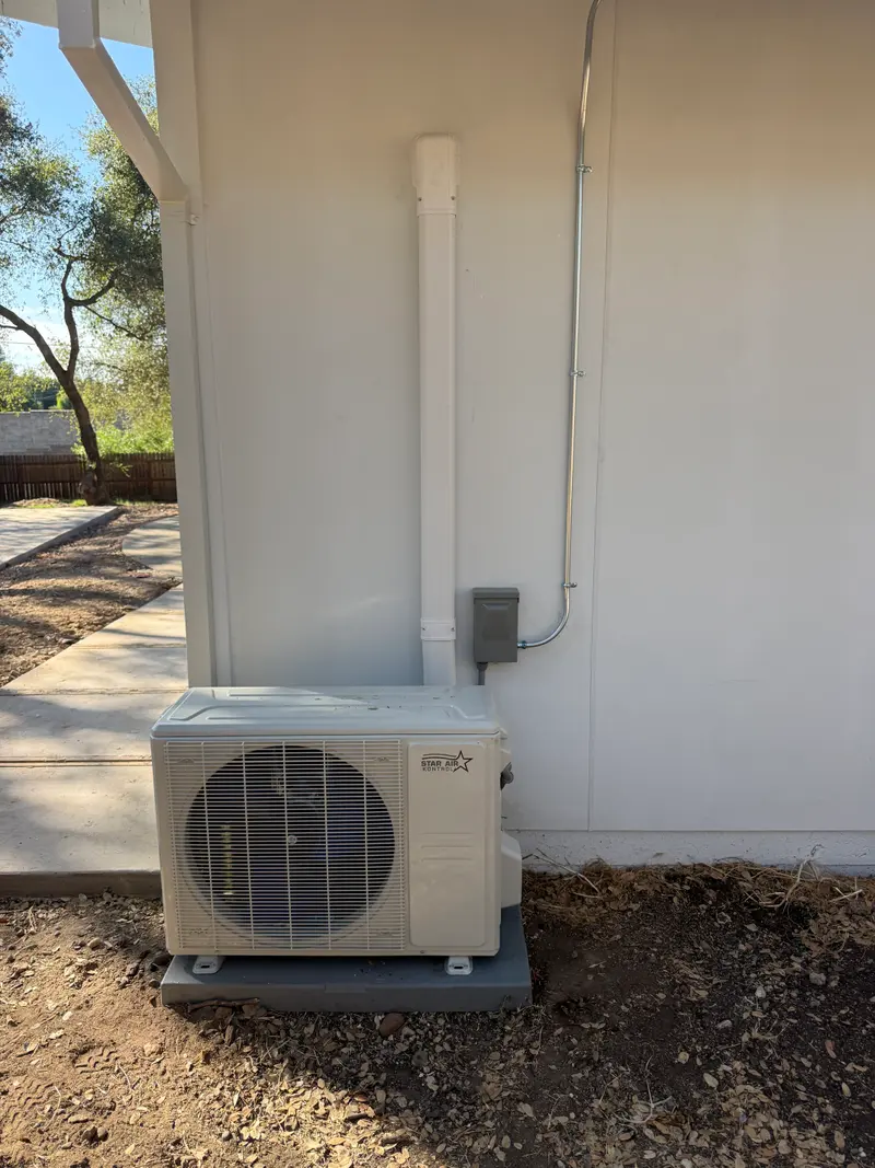 Ductless mini-split outdoor condenser on a pad with line-set cover and disconnect