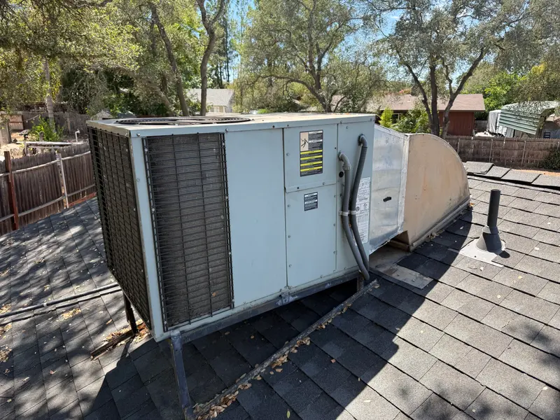 Side view of an old rooftop package HVAC unit and supply duct transition